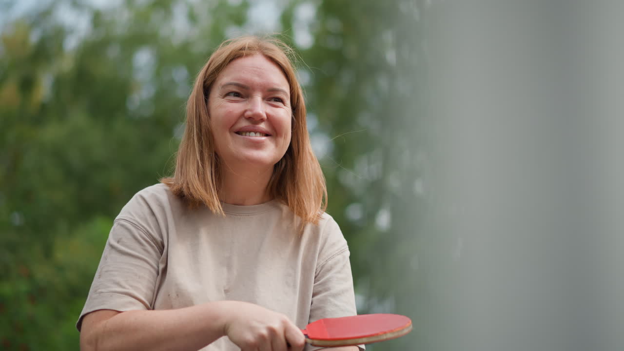 Kvinde laver sjove ansigter udendørs, glad kvinde laver komiske fagter udendørs, livlig scene med kvinde med pagaj, der laver humoristiske og livlige udtryk udendørs