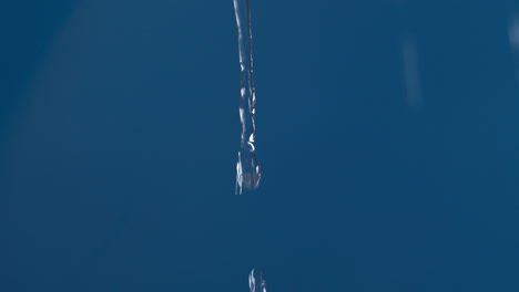 real pure water drop down with splashing on blue background shooting in slow motion