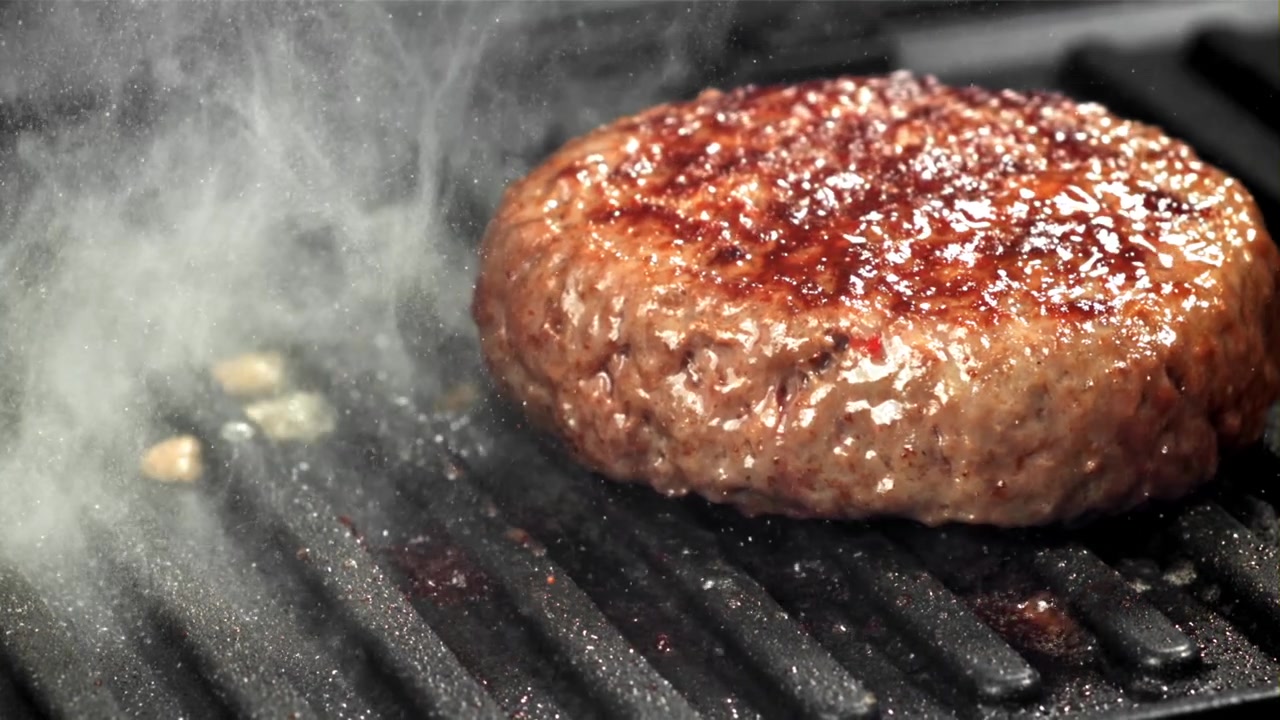 Juicy Hamburger Patty Sizzling on a Hot Grill