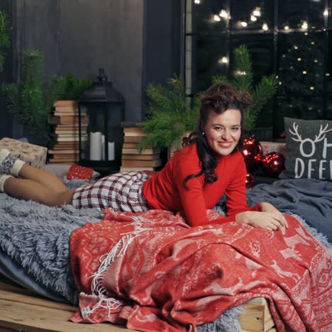 very beautiful girl rolling in bed and posing to the camera. room interior before winter holidays. fest spirit