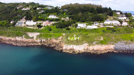 vuelo aéreo sobre la costa rocosa y el letrero eire 7 en dalkey, irlanda