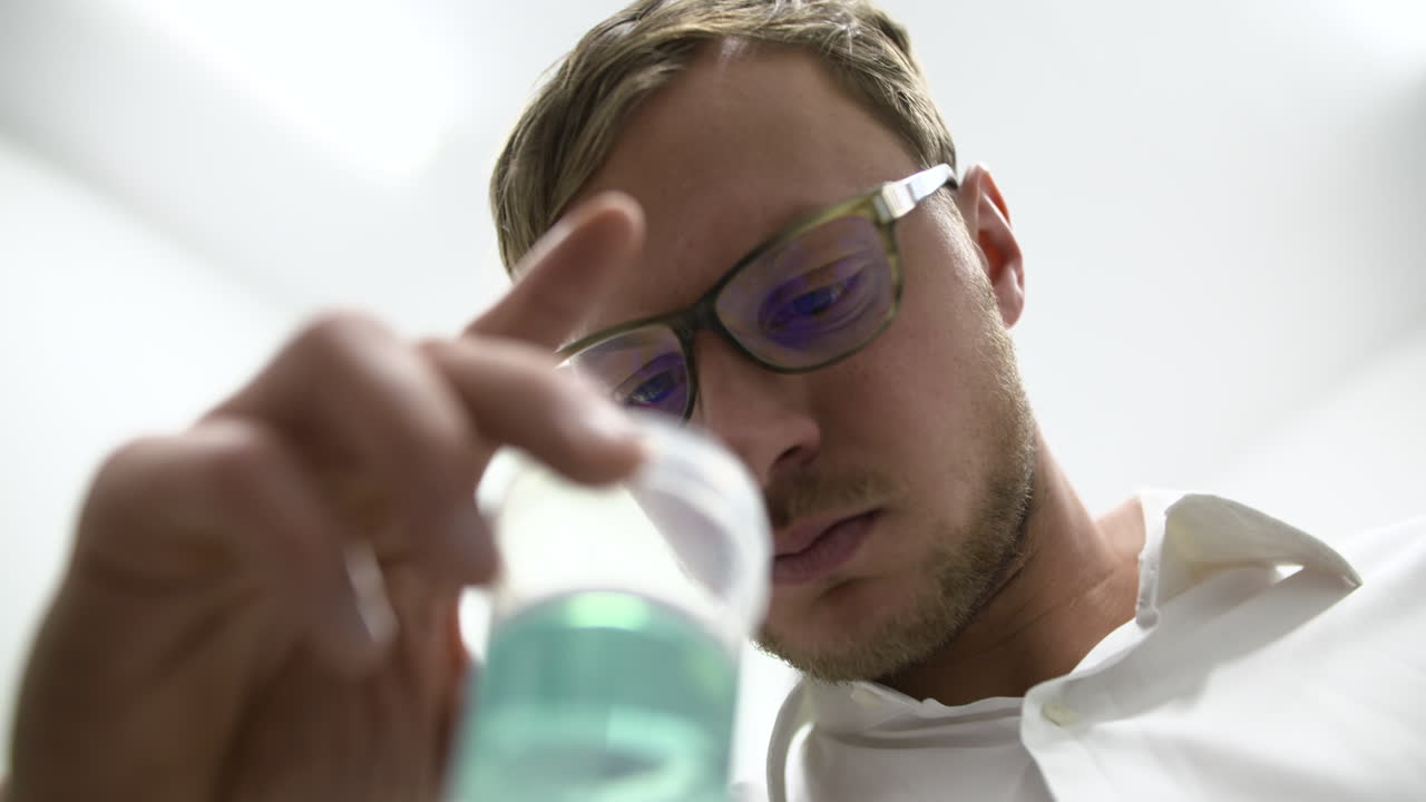 Fokussierter Wissenschaftler untersucht blaue Flüssigkeit in einem Becherglas