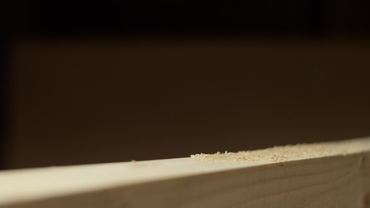 High quality video showing a craftsman sanding a wooden board in warm light with slow smooth hand movements and fine dust in the air creating a rich tactile workshop atmosphere