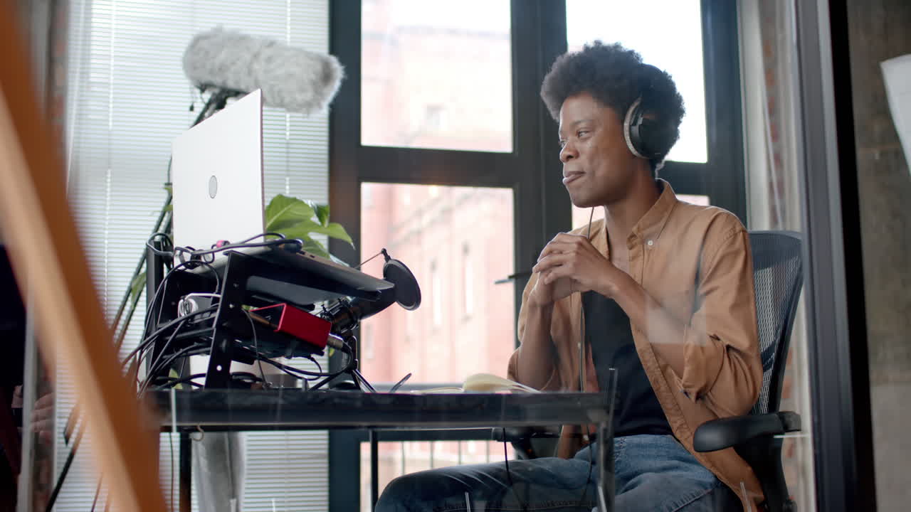 헤드폰을 착용한 행복한 아프리카계 미국인 남자가 집에서 라이브 캐스트를 만들고, 복사 공간, 느린 동작
