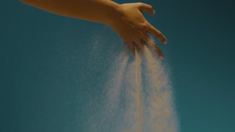 sand drifting on a person's hand on the air