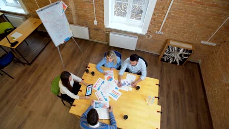 reunión de negocios en el loft espacio compartido. equipo hablando, mujer gerente dando dirección a la gente. vista superior.