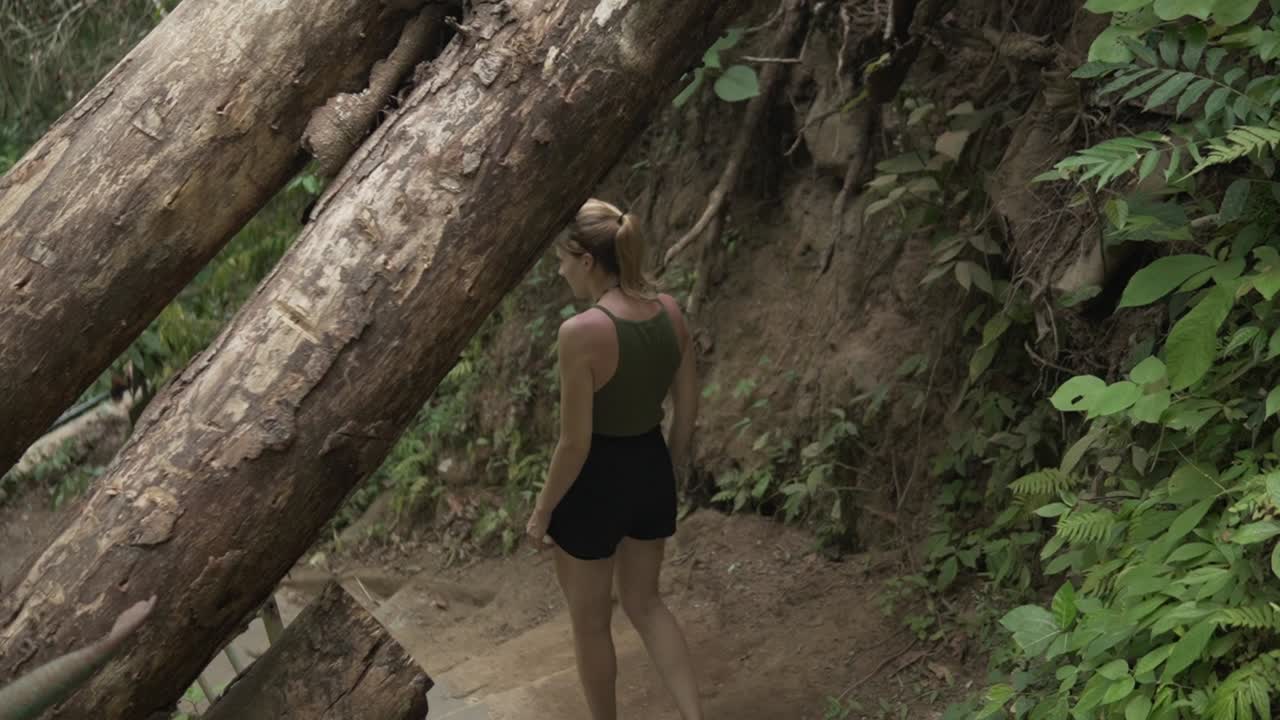 Modella in trekking che scende le scale verso una famosa cascata a Lombok, Indonesia