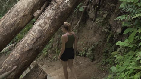 female model trekking down steps to a famous waterfall in lombok, indonesia