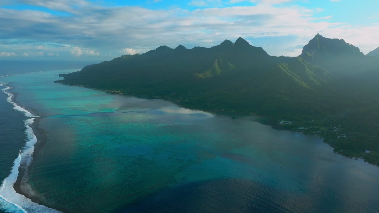 Morning sunrise Moorea island Cooks Opunohu bay French Polynesia aerial drone lagoon coral reef Mount Mauaroa Tohivea Rotui jagged peaks Haapiti Paopao Pacific Ocean blue sky sun flare circle left