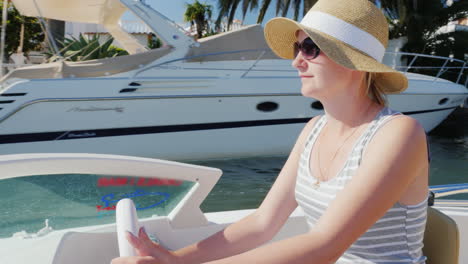 Young-Woman-Tourist-With-Sunglasses-Sitting-At-The-Controls-Of-A-Small-Boat-Floating-Empuriarava-Cha