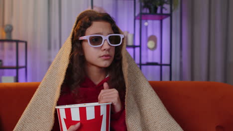 oreteen girl eating popcorn, watching interesting tv serial, sport game online content on home couch