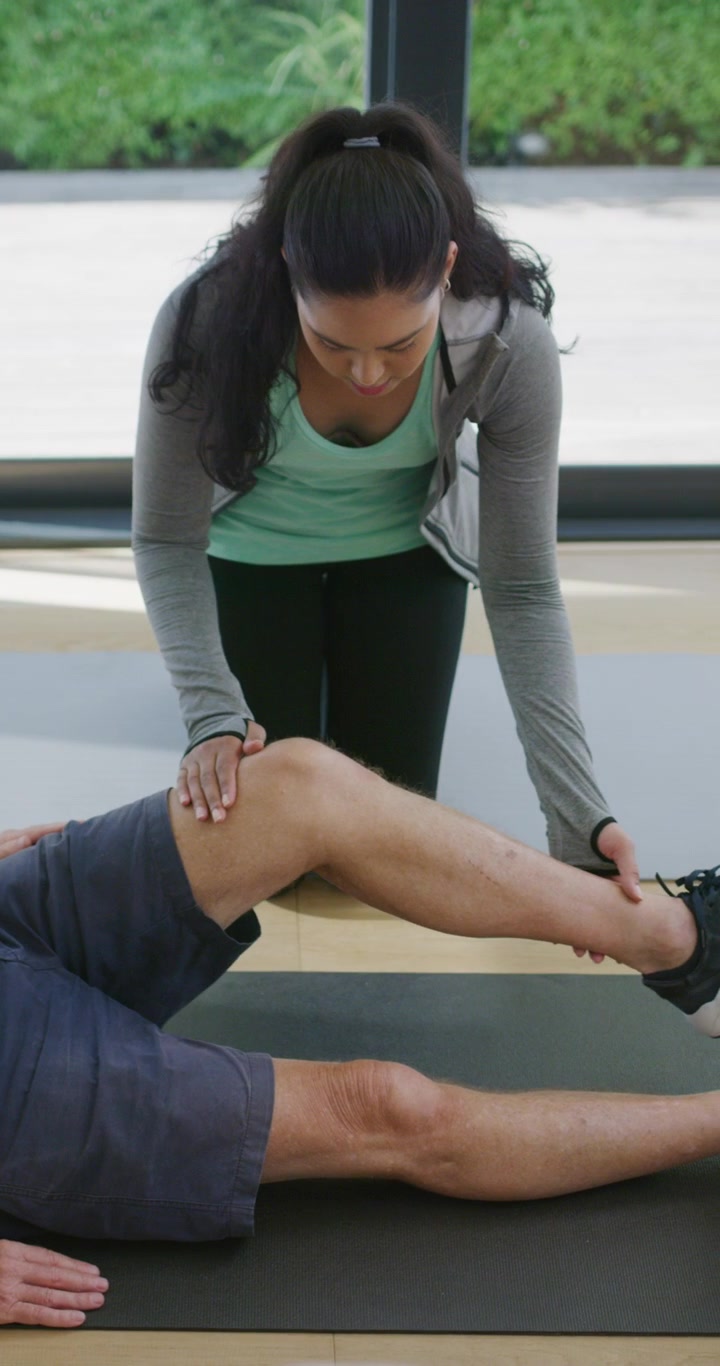 Physical Therapist Assisting Senior Man with Leg Stretching Exercise
