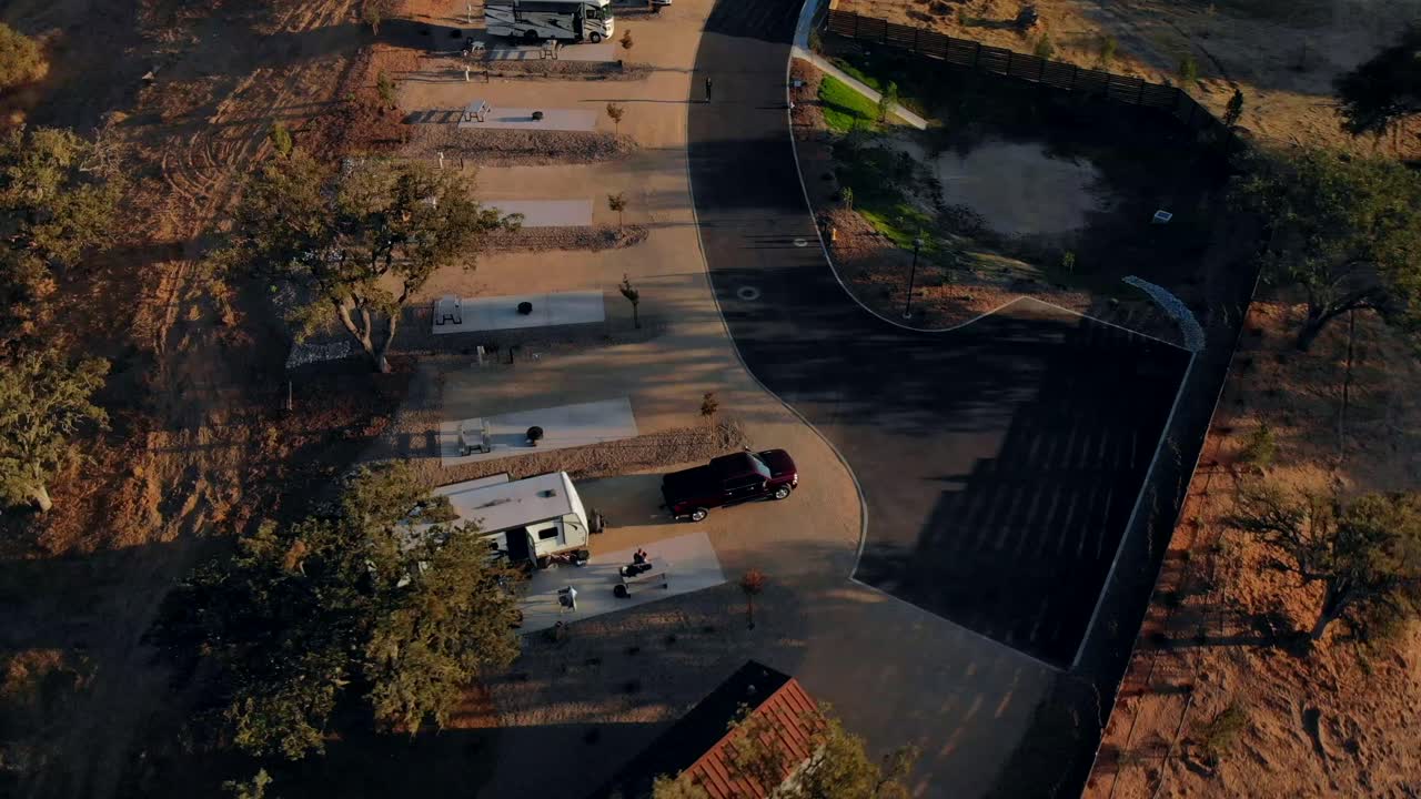 Aerial view rotating and pulling back of an RV trailer in an RV park at sunset