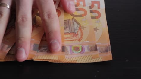 closeup of hands showing 50 euros banknotes money, black background, static