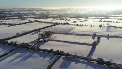 Frío-Invierno-Nevado-Británico-Mosaico-Tierras-De-Cultivo-Campo-Rural-Escena-Aérea-Al-Amanecer-órbita-Cinematográfica-Izquierda