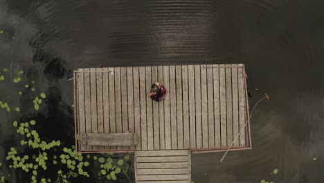 Beautiful-girl-dancing-on-wooden-path-near-lake-from-above