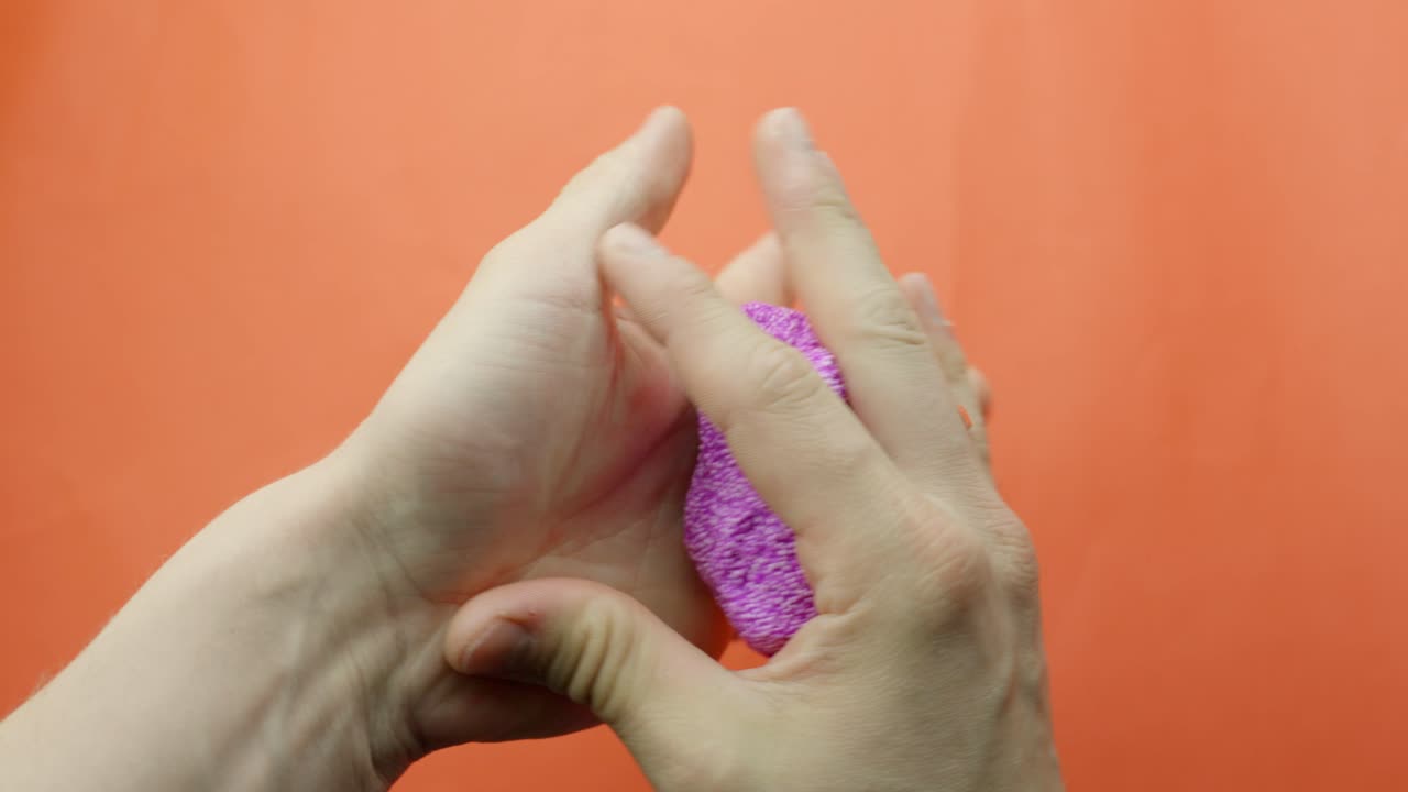 Pink Floam slime is kneaded slowly for ASMR against a vibrant red background, creating textured sounds.