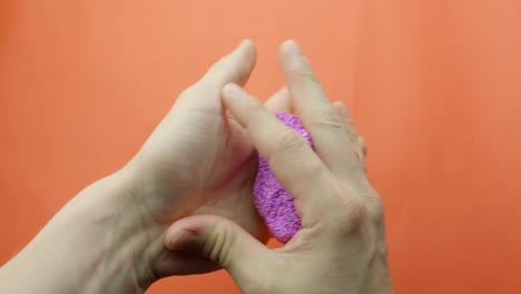 pink floam slime is kneaded slowly for asmr against a vibrant red background, creating textured sounds.