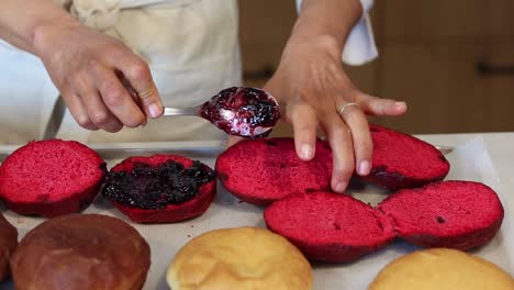 crop cook adding jam on sponge cakes in bakehouse