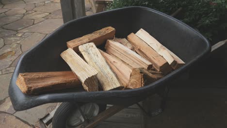 still view of a black wheelbarrow loaded with chopped wood in the backyard