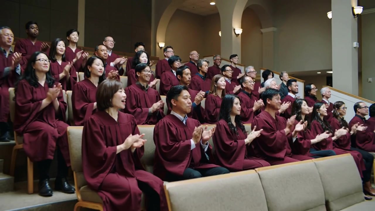 Clapping foreground man in maroon choir robe responding to off-camera conductor cue at sanctuary