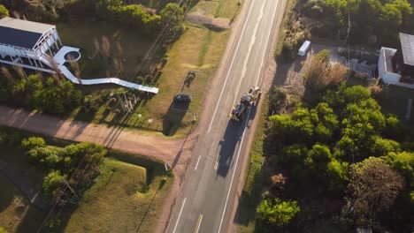 Yellow-tractor-with-crane-driving-and-turning-from-dirt-to-main-road-of-residential-area-od-Punta-del-Este-in-Uruguay