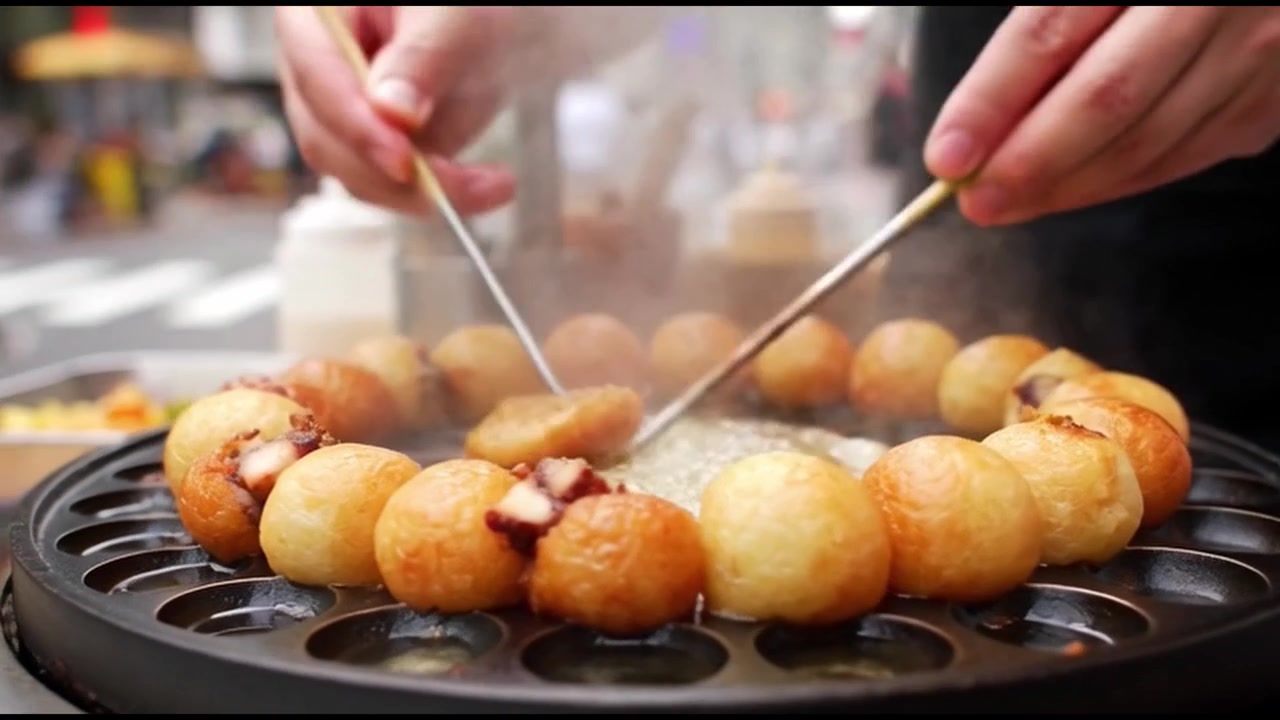 Venditore ambulante che cucina Takoyaki freschi su una piastra calda