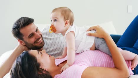 padres jugando con su niña en el dormitorio