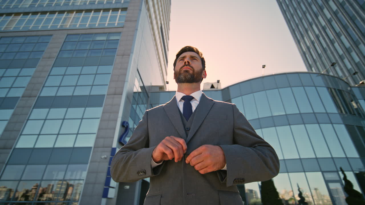 gerente barbudo posando en el centro abotonando una chaqueta elegante.