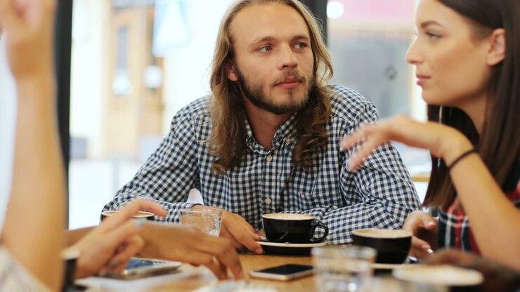 Close-up view of multiethnic group of friends talking sitting at a table in a cafe