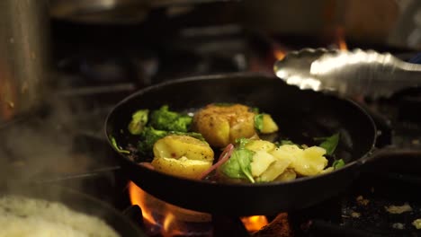 slowmo - nahaufnahme - braten von gedämpftem, frischem, grünem brokkoli, spinat, zwiebeln und kartoffeln am feuer