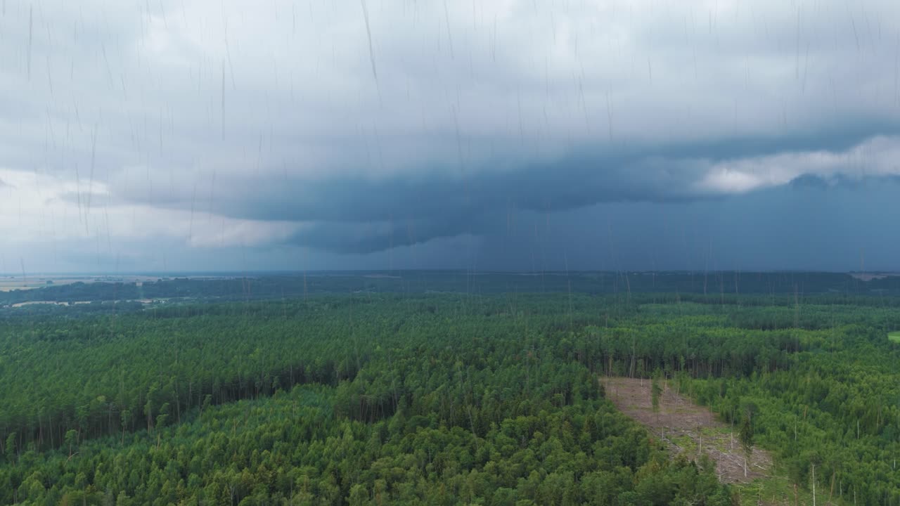 Dark storm clouds and rainfall over Lithuania woodland, aerial drone view