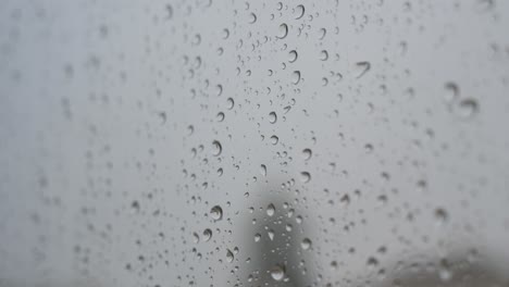 detailed raindrops on a window looking out to gloomy, overcast weather