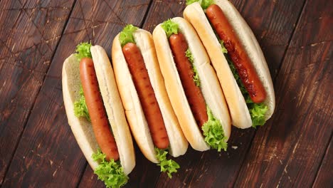 맛있는 미국식 핫도그가 나무 테이블에 줄지어 놓여 있습니다.