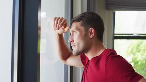 Thoughtful-caucasian-man-is-looking-out-the-window