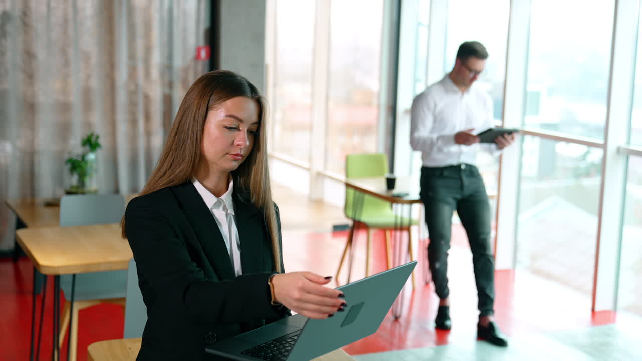 People working freelance using their gadgets. Woman closes her laptop and smiles to the camera.