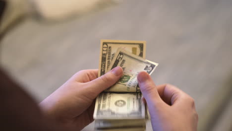 over shoulder shot of woman hands counting dollar bills