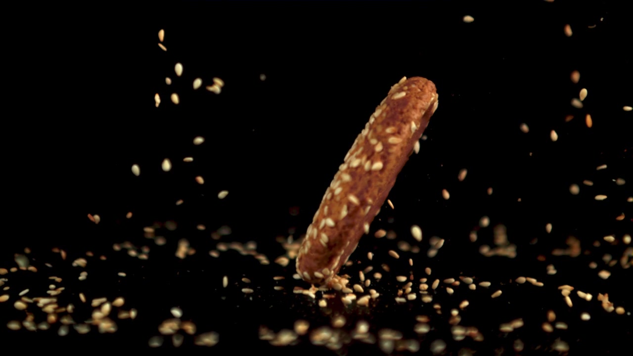 Delizioso biscotto al sesamo che cade al rallentatore su uno sfondo nero.