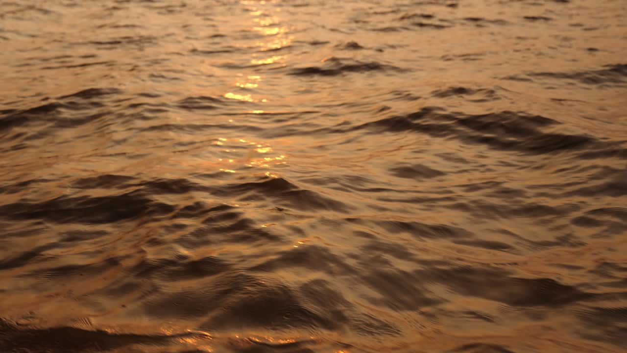 Sunset light reflects softly on Tonle Sap Lake ripples in warm golden tones