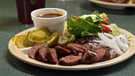 Close-up-shot-of-fried-meat-fillet-along-with-fresh-vegetable-salad-of-tomatoes,-cucumbers,-onion-and-lettuce-been-served-on-a-white-plate-with-sauce