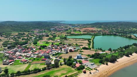 Toma-Aérea-Hacia-Atrás-De-La-Isla-Kinmen-金門-Con-Ciudad,-Lago-Y-Barrera-Antiaterrizaje-En-La-Playa-De-Arena-En-Verano---Protección-Contra-Ataques-De-Guerra