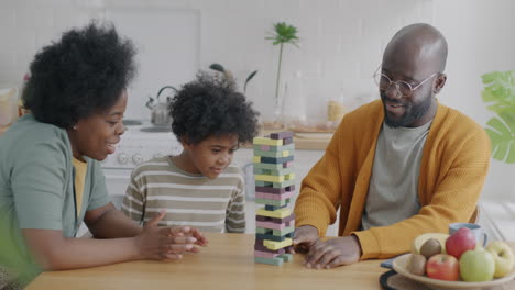 family playing stacking blocks game in kitchen