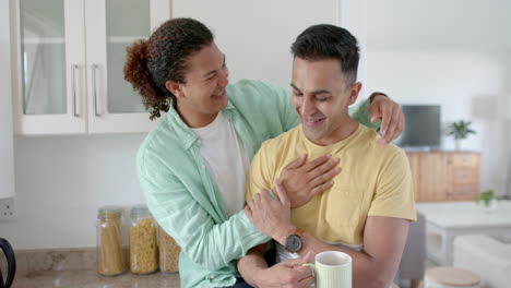 feliz pareja gay diversa tomando café y abrazándose en la cocina soleada, cámara lenta