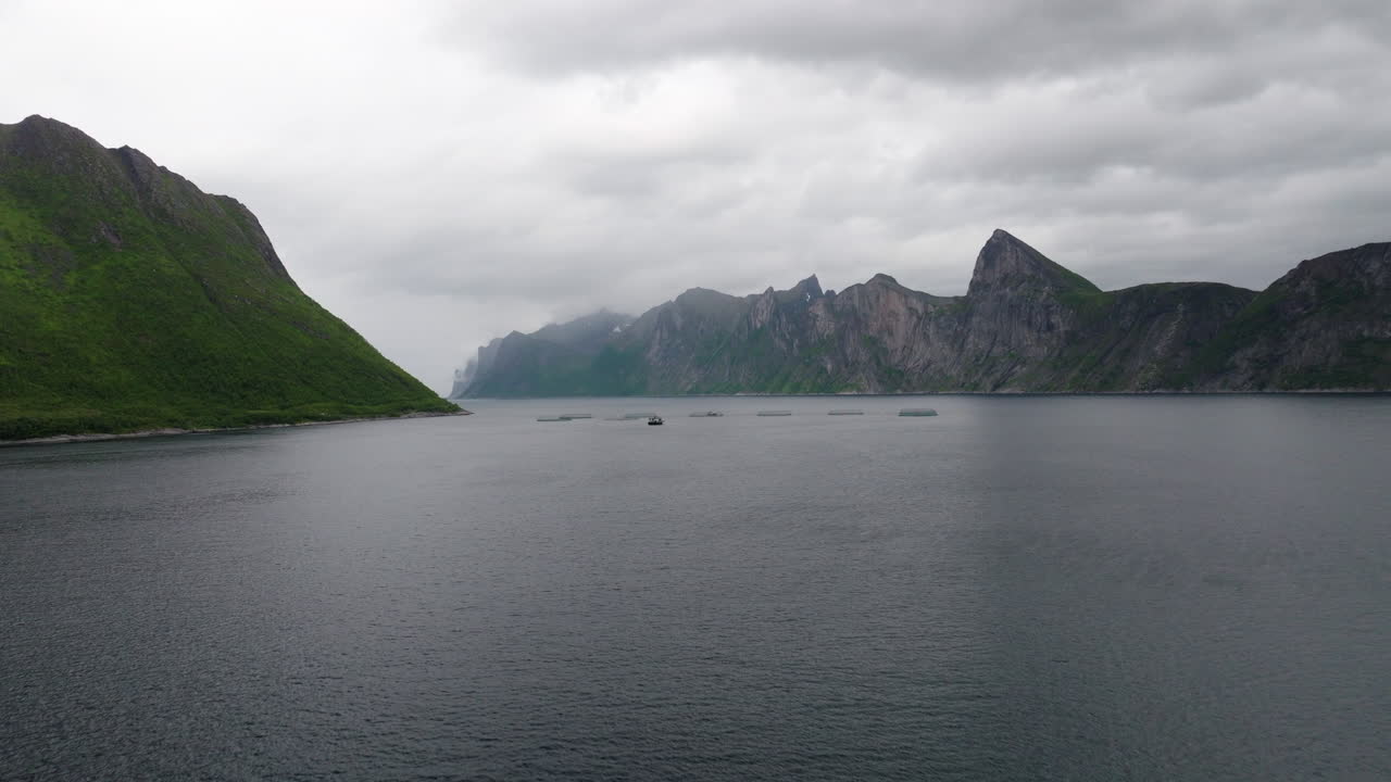 Aerial toward salmon aquafarm in Mefjord Norway surrounded by dramatic mountains