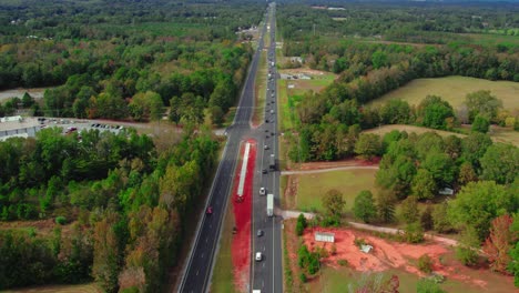 El-Remolque-De-Camión-De-Carga-Industrial-Pesada-De-Madera-Entra-En-El-Marco-Con-Grandes-Pinos,-Abetos-Y-Cedros-Conduciendo-Por-La-Carretera