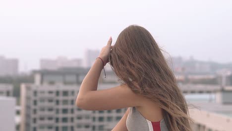 화가 난 소녀는 호텔 지붕에서 손으로 긴 어두운 머리카락을 고쳐줍니다.