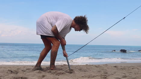 Man-removing-ground-stakes-from-the-sand.