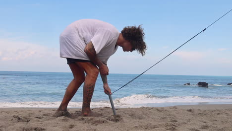 man removing ground stakes from the sand.