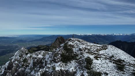 person standing on a snowy mountain peak with a cross
