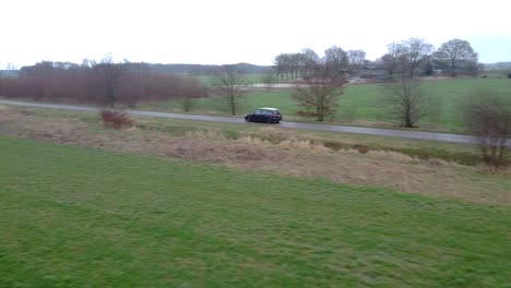 car-driving-off,-pan-to-view-of-a-large-meadow